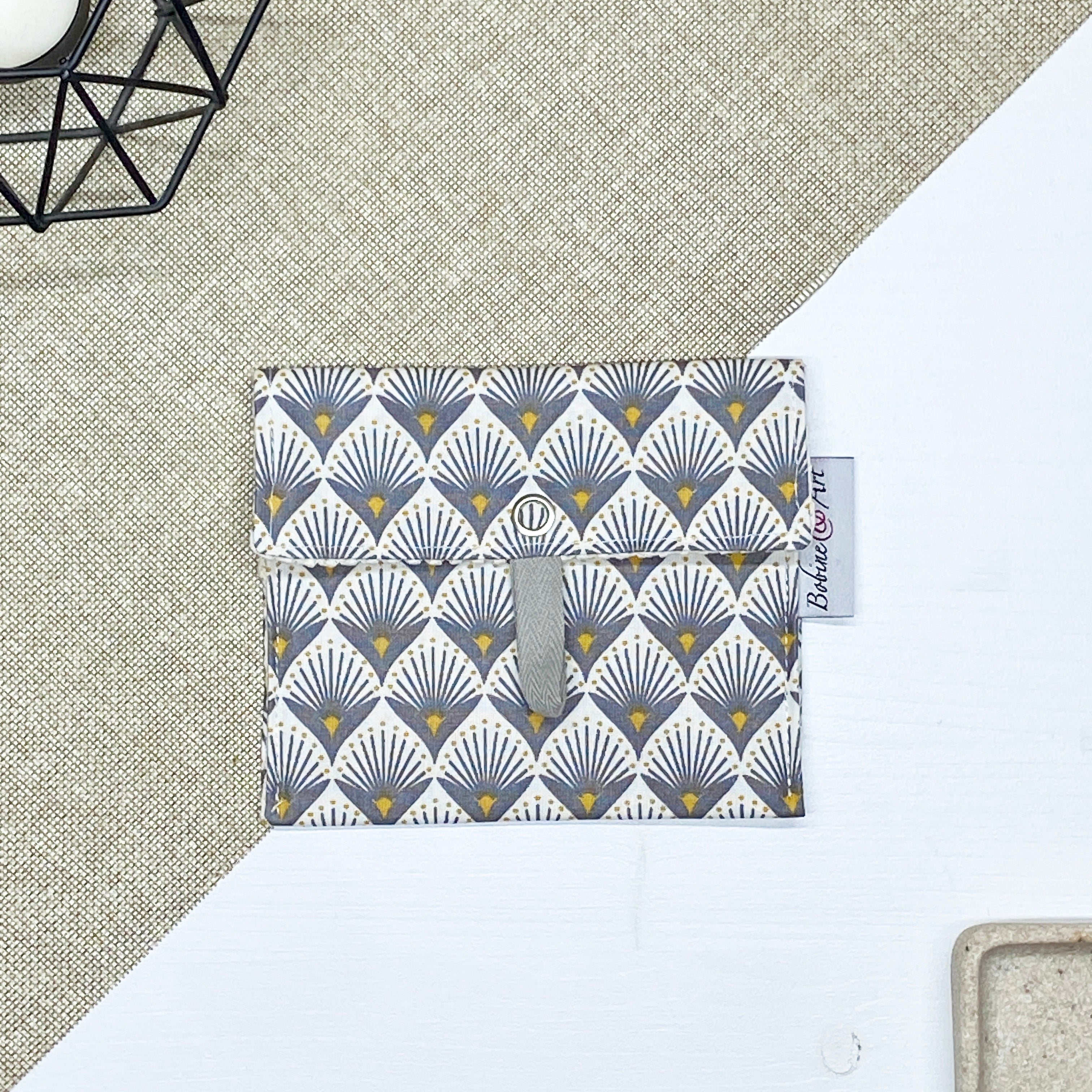 Porte-savon nomade imperméable fermé à motif éventails Art déco gris et jaune moutarde sur fond écru, format compact idéal pour transporter un savon solide lors des déplacements, voyages ou activités du quotidien.