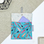 Porte-savon nomade imperméable à motif maquillage avec rouges à lèvres, pinceaux et crayons sur fond bleu turquoise, idéal pour transporter un savon solide ou des accessoires de toilette en déplacement.