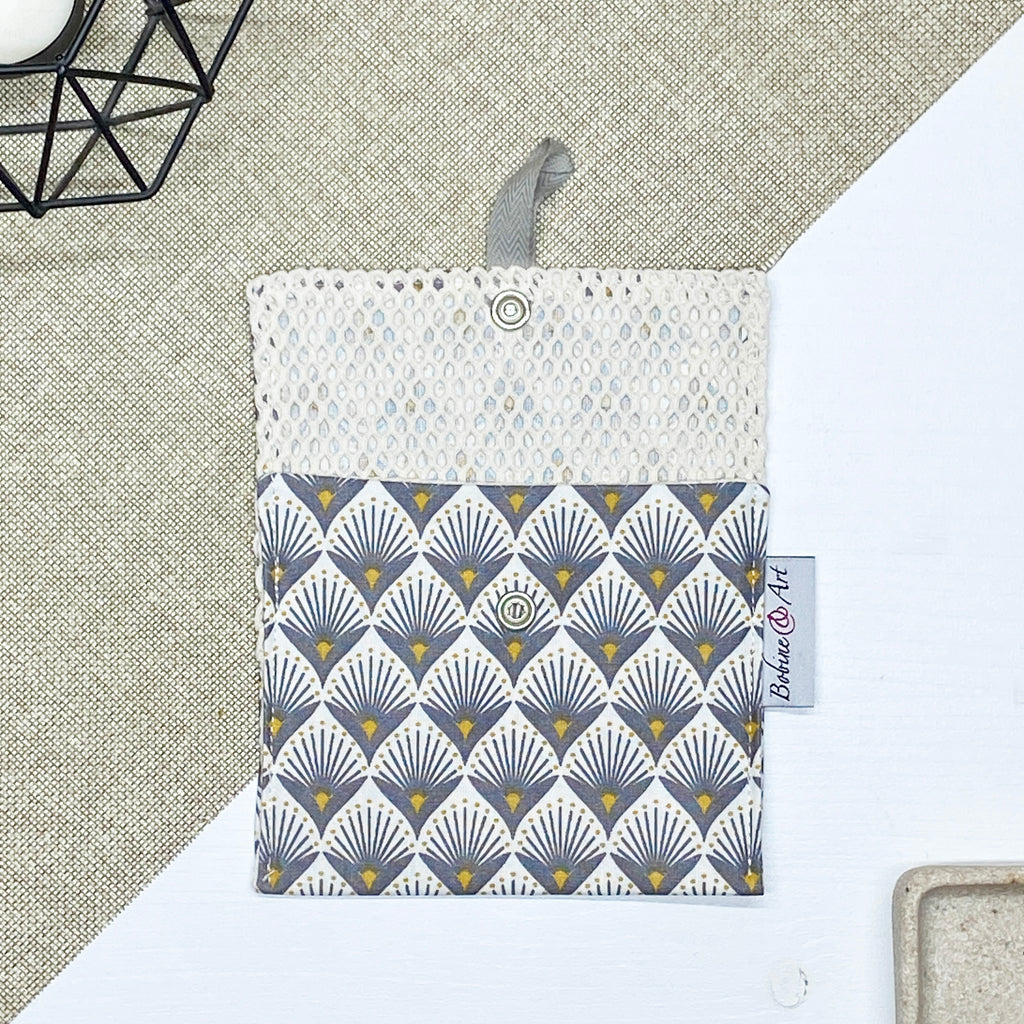 Porte-savon nomade imperméable ouvert avec filet respirant et motif éventails Art déco gris et jaune moutarde sur fond écru, idéal pour transporter, faire sécher et conserver un savon solide lors des déplacements et voyages.