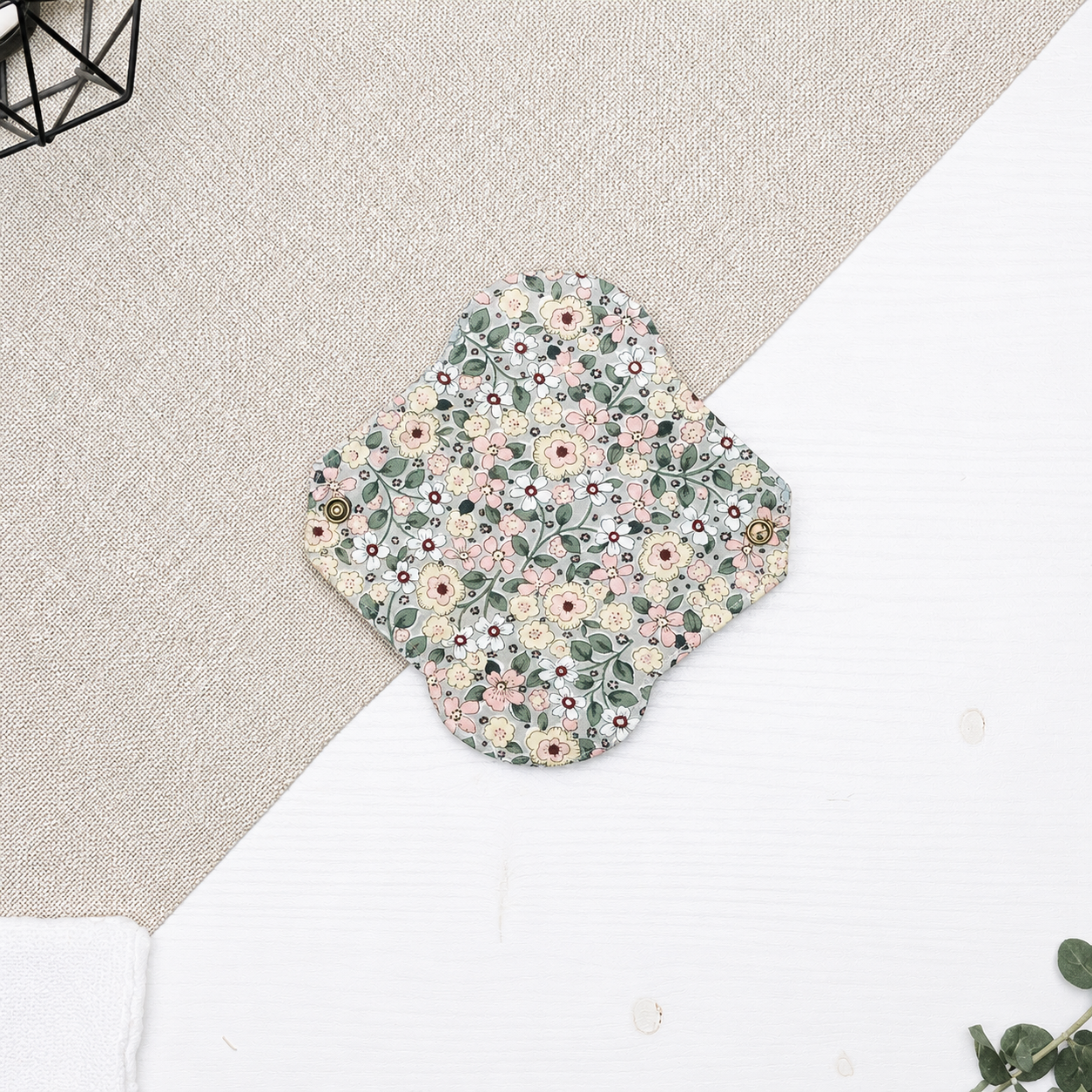 Serviette hygiénique lavable flux léger à motif fleurs champêtres roses et écrues sur fond vert sauge, protection périodique réutilisable idéale pour le début ou la fin des règles et les flux légers.