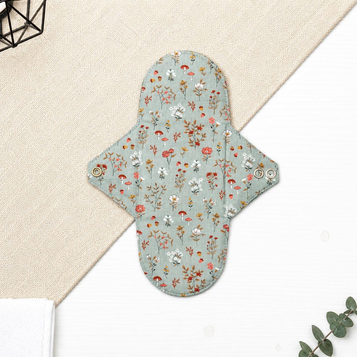Serviette hygiénique lavable flux normal à motif fleurs sauvages, feuillages et champignons sur fond bleu grisé, protection périodique réutilisable à forte absorption adaptée aux flux normaux.