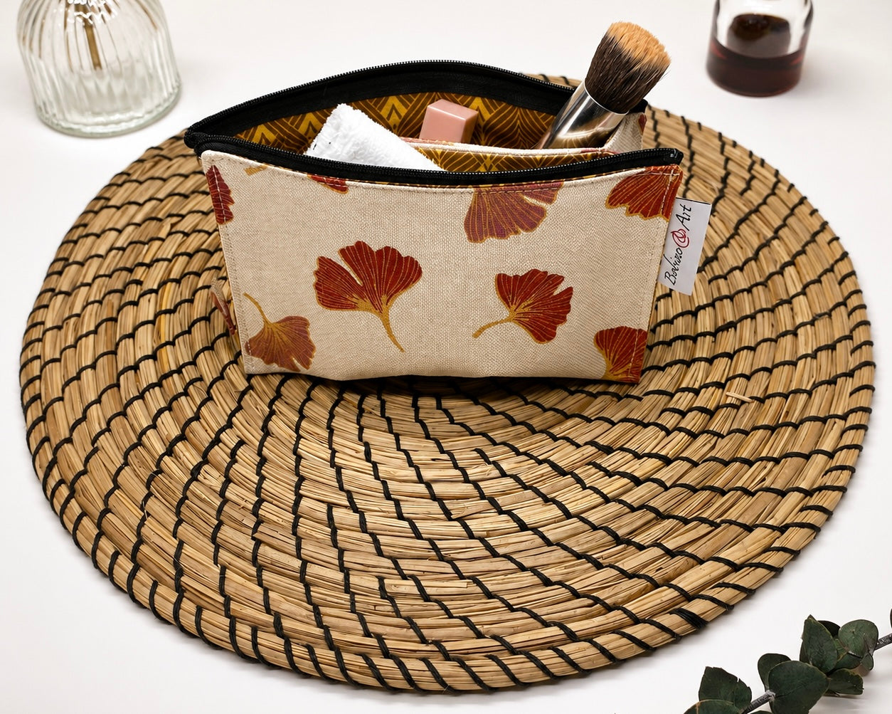 Trousse de toilette artisanale à motif feuilles de ginkgo avec accessoires de maquillage.