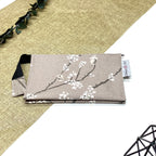 Trousse de toilette artisanale fermée en tissu avec motif branches fleuries blanches et double compartiment imperméable.