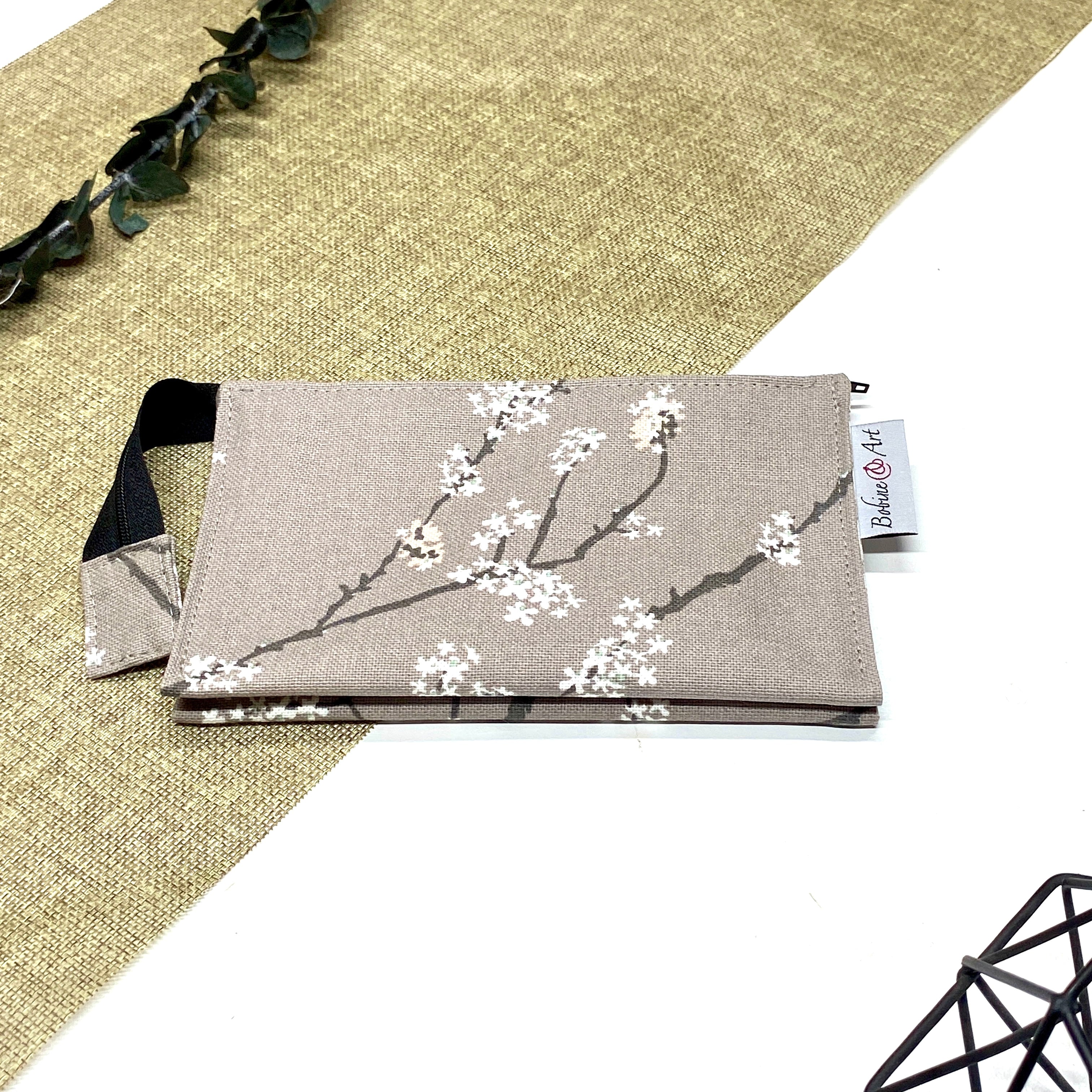 Trousse de toilette artisanale fermée en tissu avec motif branches fleuries blanches et double compartiment imperméable.