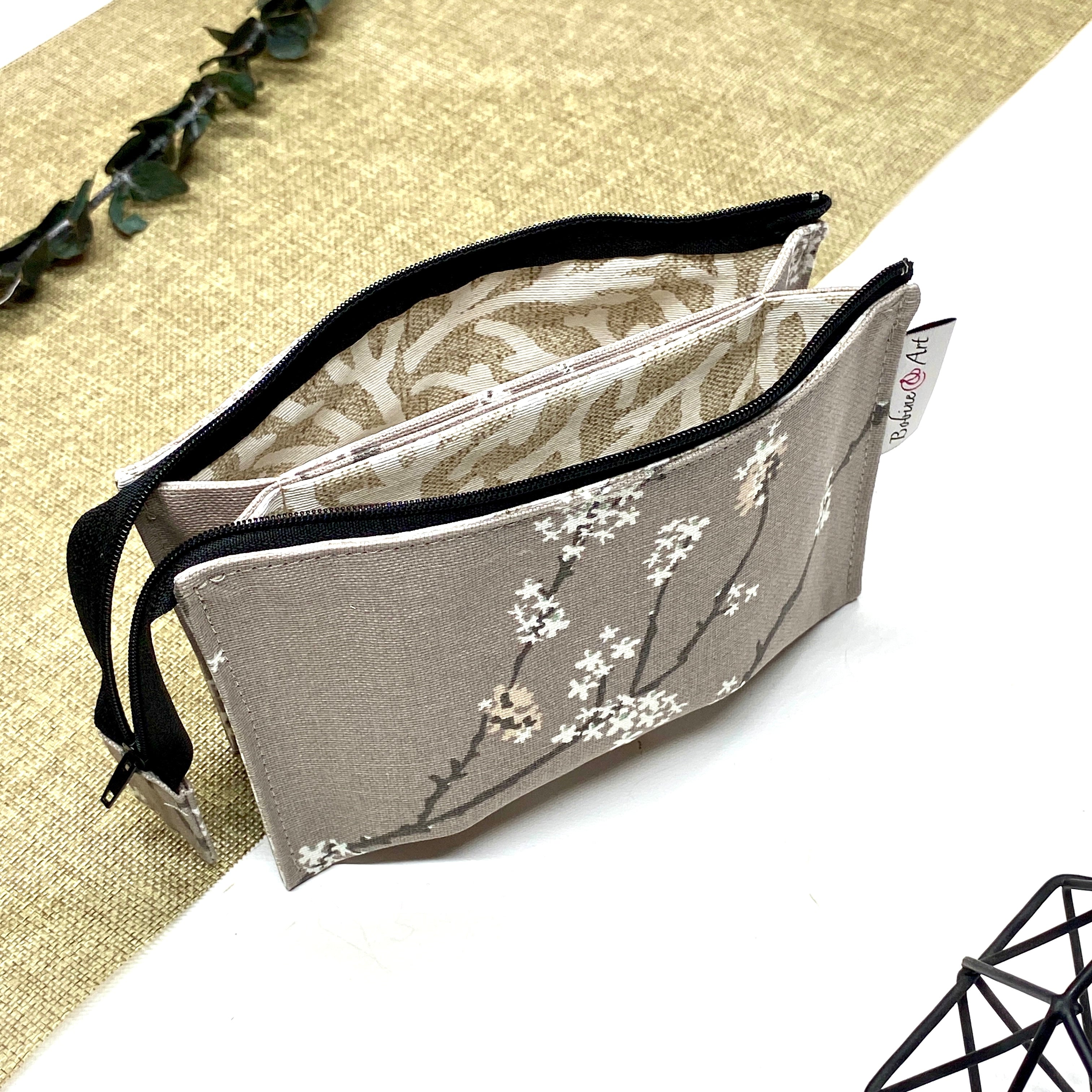Trousse de toilette artisanale ouverte en tissu avec motif branches fleuries blanches, double compartiment et intérieur imperméable.