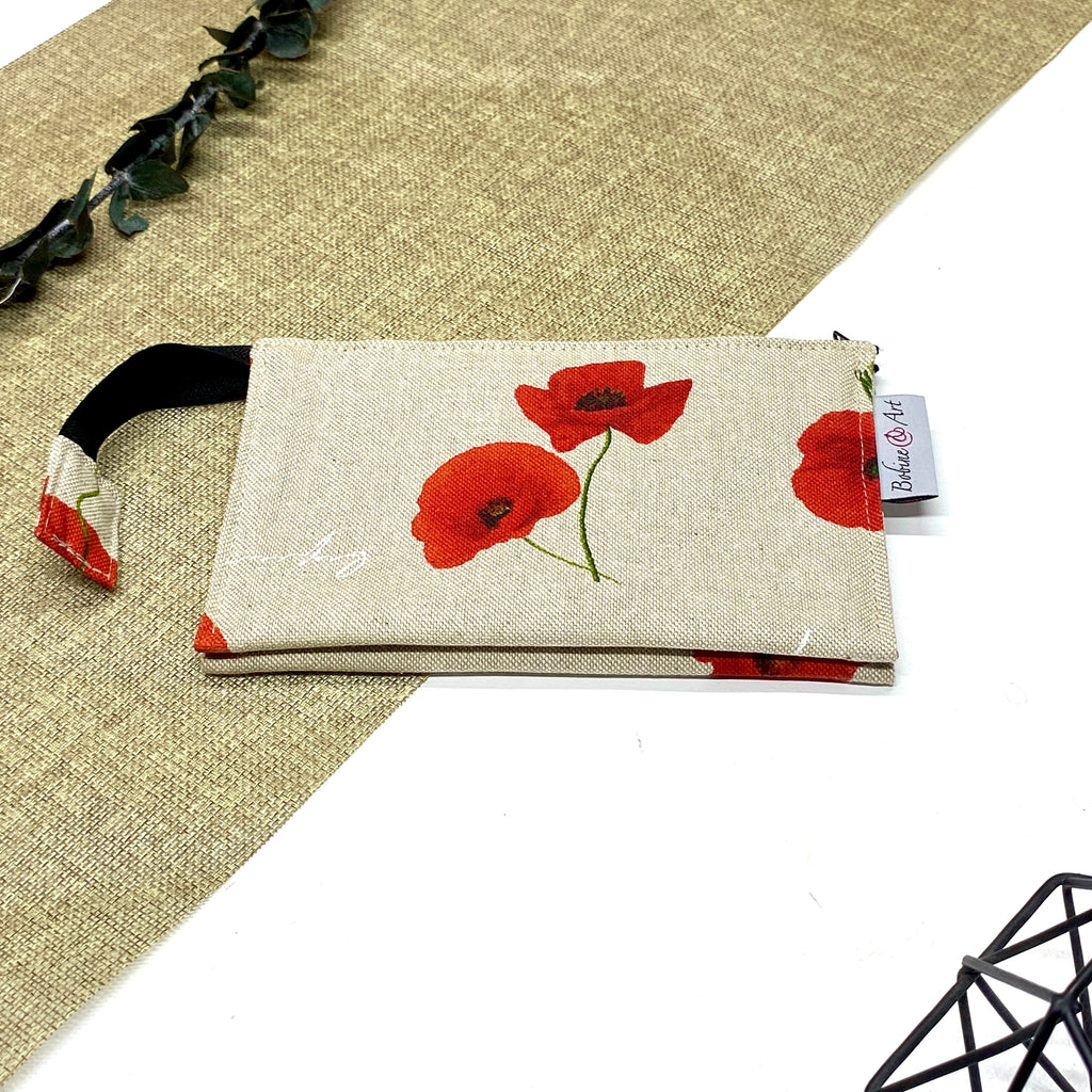 Trousse de toilette artisanale fermée en tissu avec motif coquelicots rouges et double compartiment imperméable.