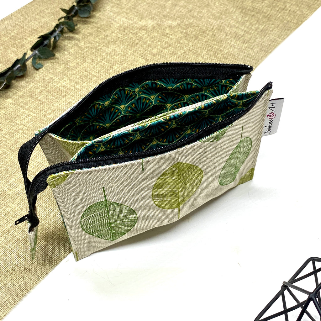 Trousse de toilette artisanale ouverte en tissu avec motif feuilles rondes vertes, double compartiment et intérieur imperméable.