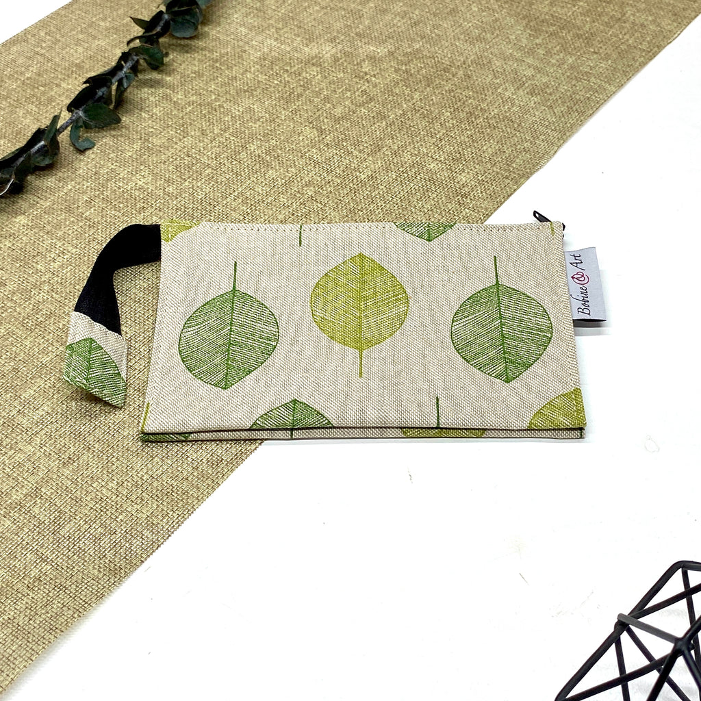 Trousse de toilette artisanale fermée en tissu avec motif feuilles vertes et double compartiment imperméable.
