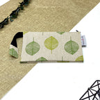 Trousse de toilette artisanale fermée en tissu avec motif feuilles vertes et double compartiment imperméable.