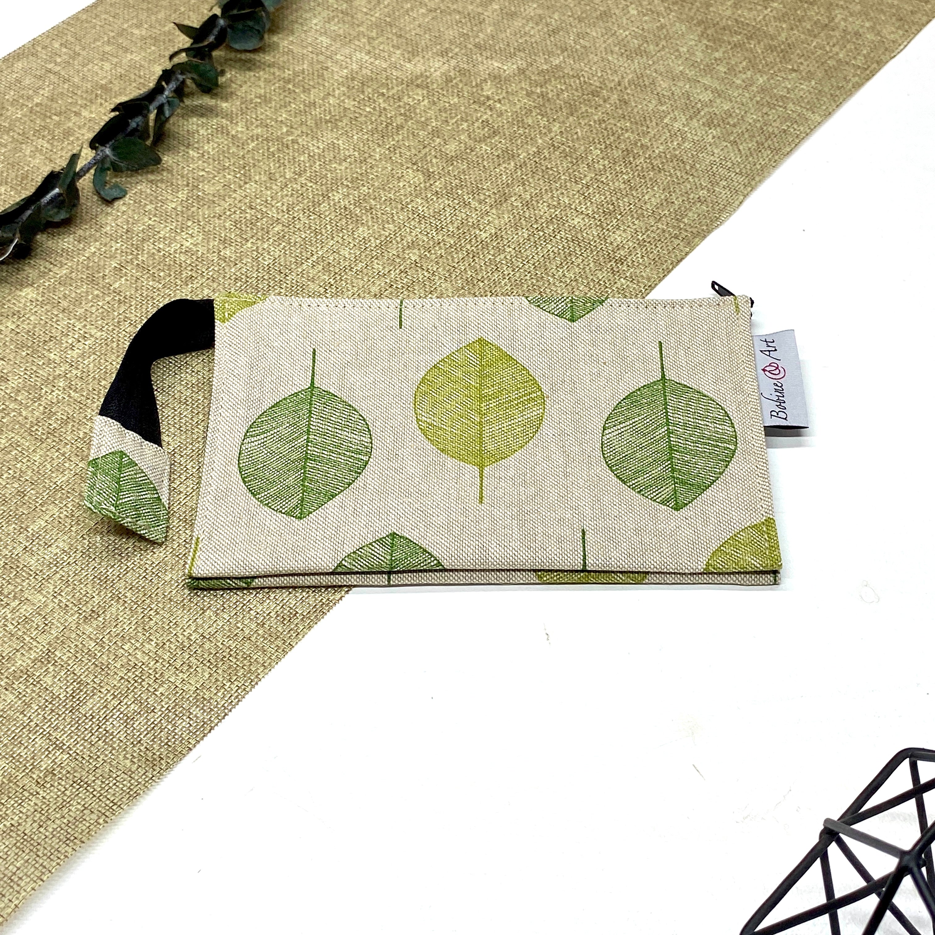 Trousse de toilette artisanale fermée en tissu avec motif feuilles vertes et double compartiment imperméable.