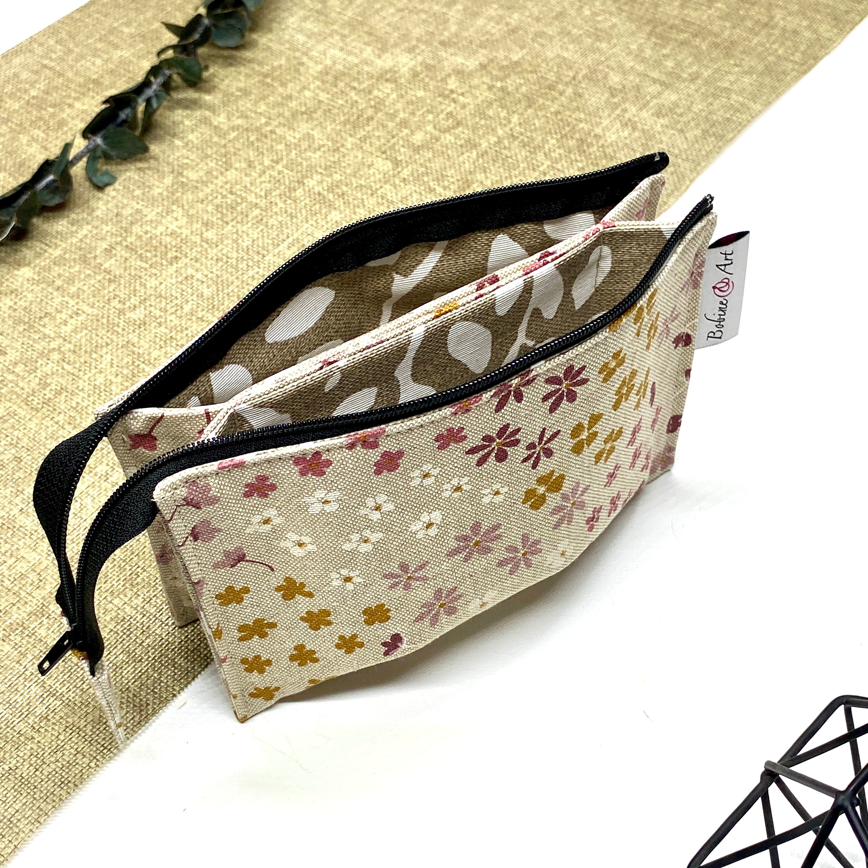 Trousse de toilette artisanale ouverte en tissu avec motif fleurs champêtres, double compartiment et intérieur imperméable.