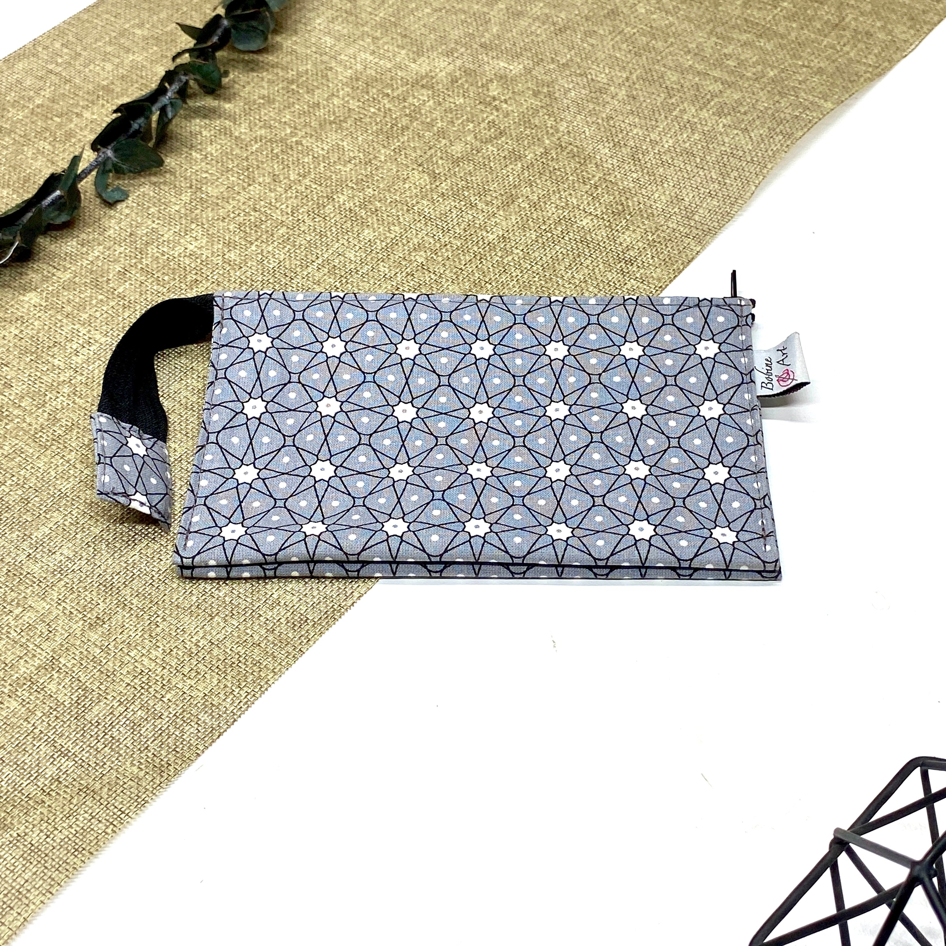 Trousse de toilette artisanale fermée en tissu avec motif géométrique gris et blanc et double compartiment imperméable.