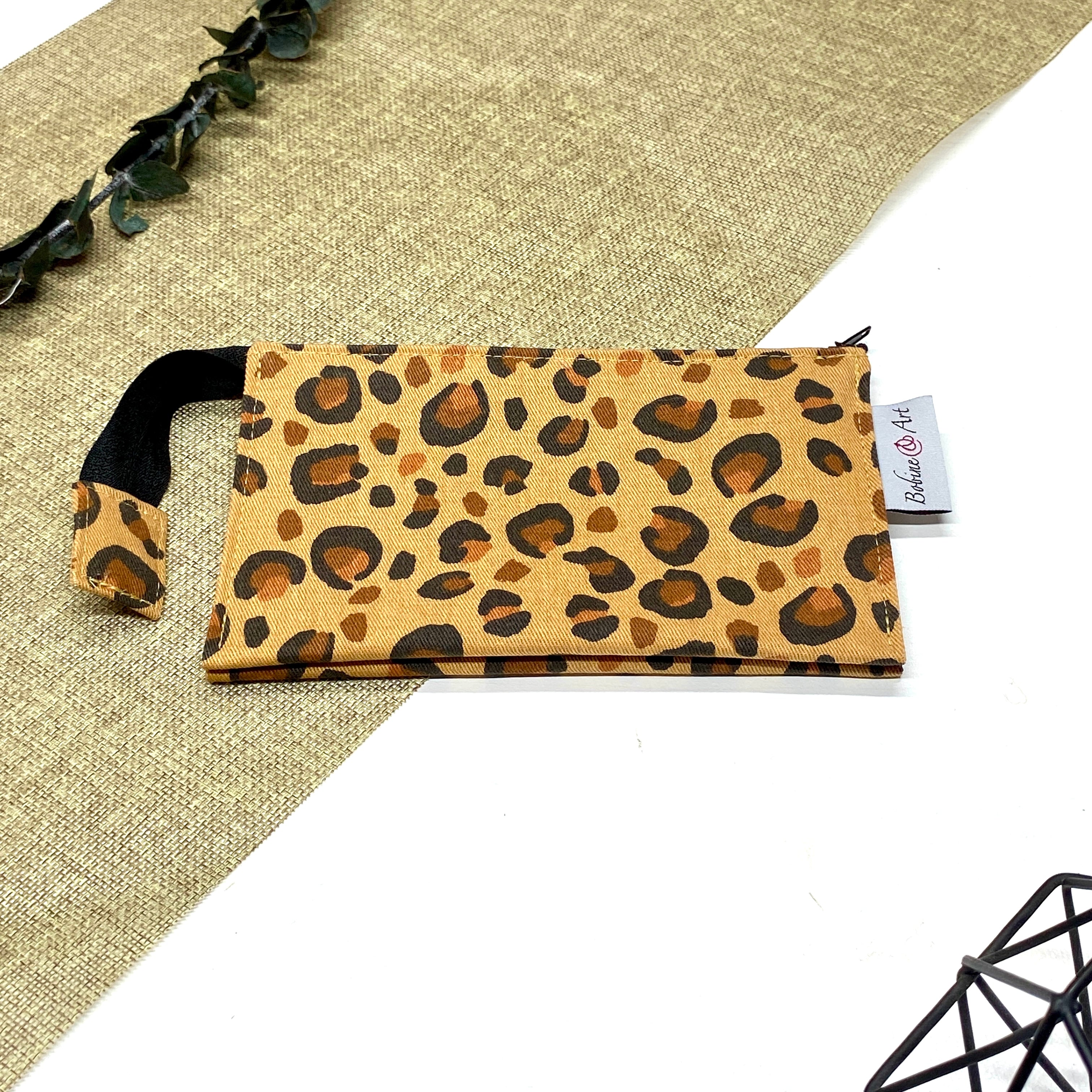 Trousse de toilette artisanale fermée en tissu avec motif léopard et double compartiment imperméable.