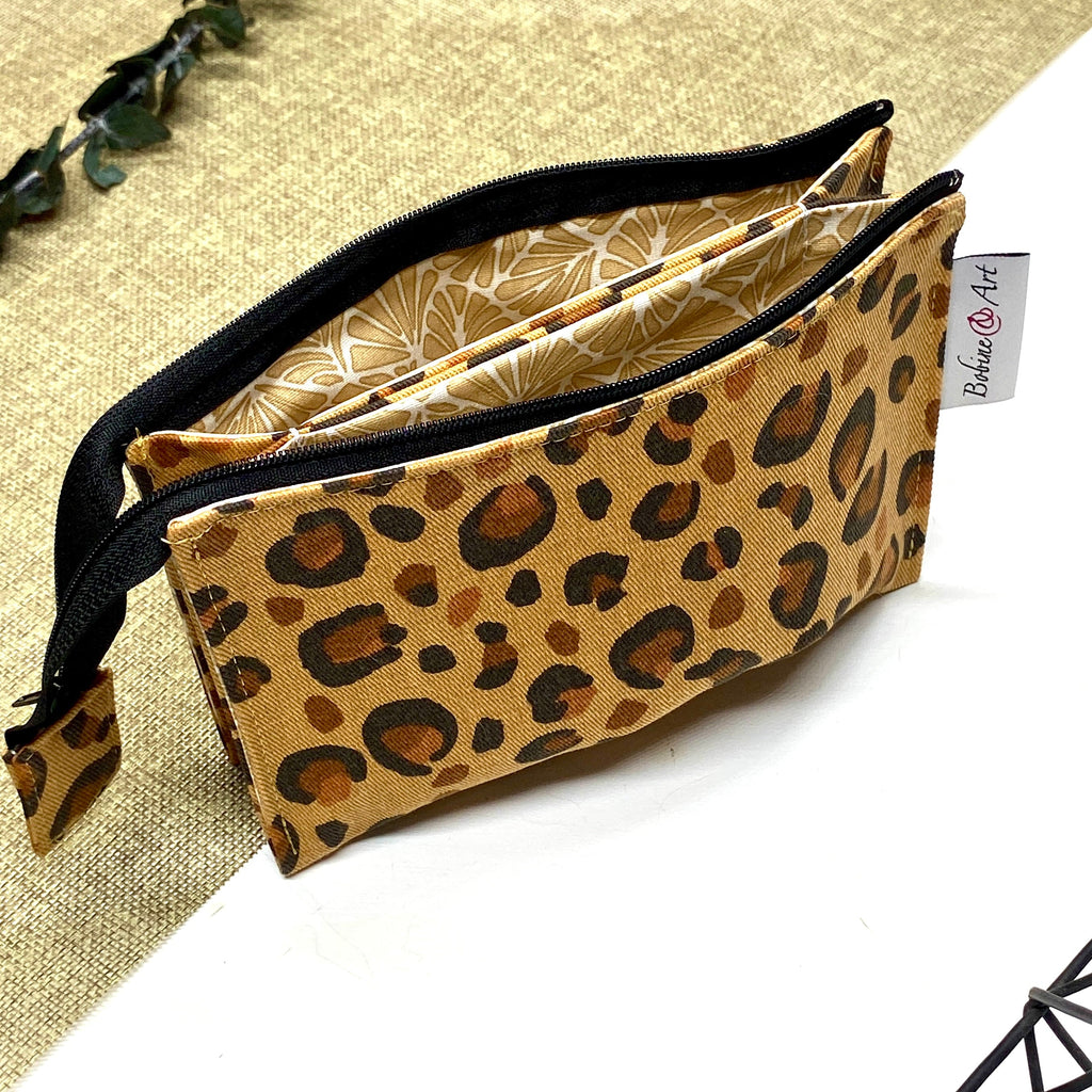 Trousse de toilette artisanale ouverte en tissu avec motif léopard, double compartiment et intérieur imperméable.
