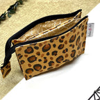 Trousse de toilette artisanale ouverte en tissu avec motif léopard, double compartiment et intérieur imperméable.