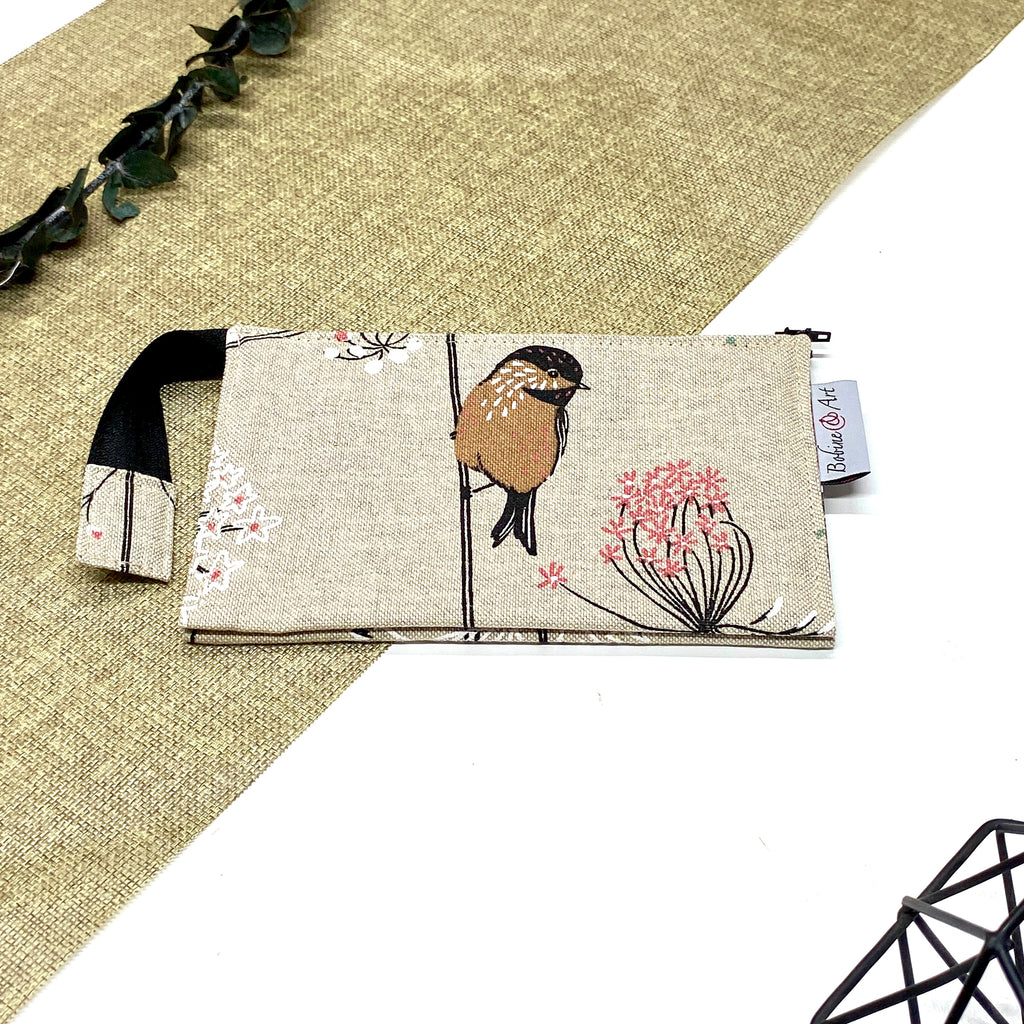 Trousse de toilette artisanale fermée en tissu avec motif oiseau sur branche fleurie et double compartiment imperméable.