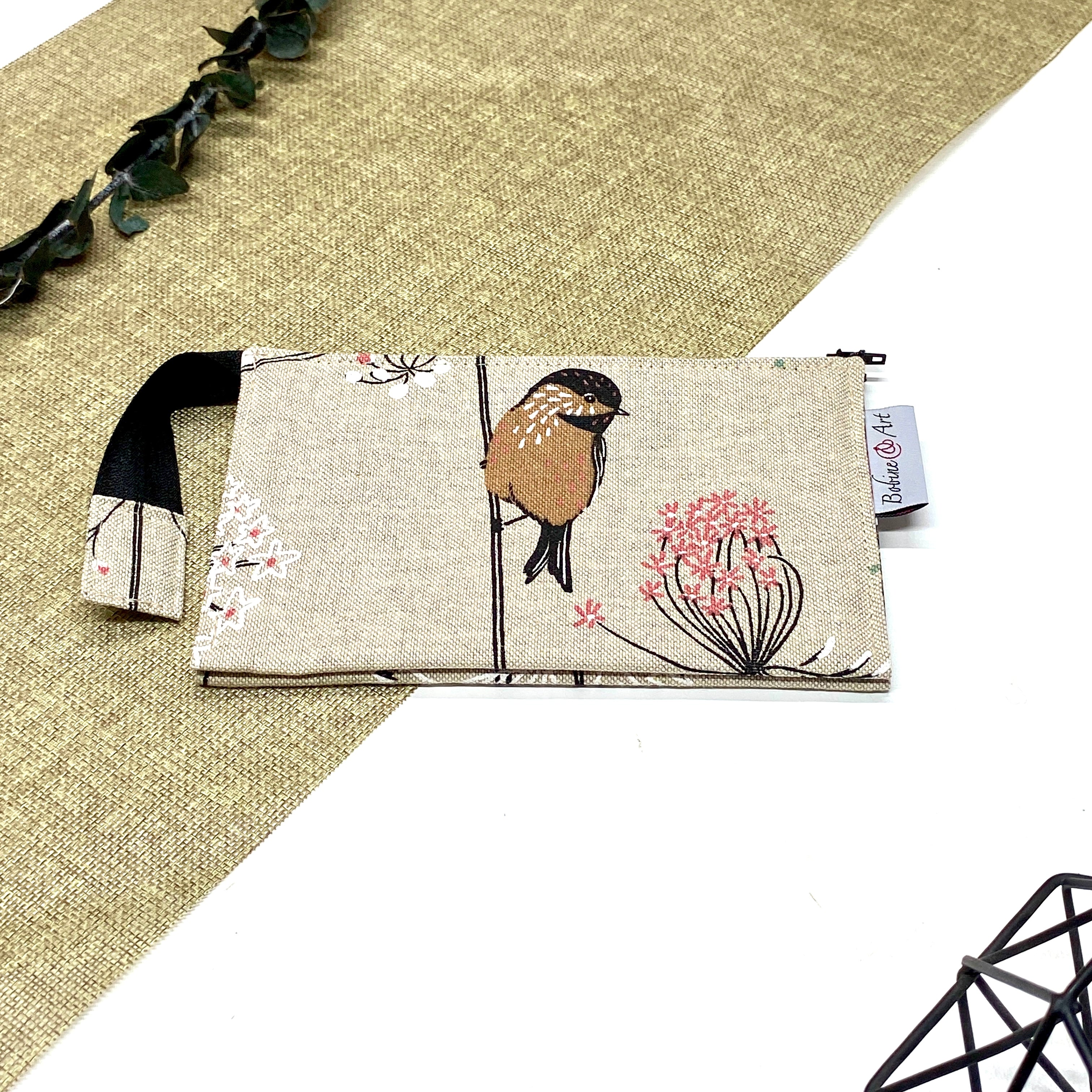 Trousse de toilette artisanale fermée en tissu avec motif oiseau sur branche fleurie et double compartiment imperméable.