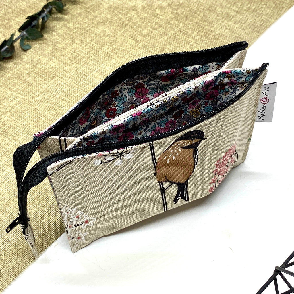 Trousse de toilette artisanale ouverte en tissu avec motif oiseaux et fleurs, double compartiment et intérieur imperméable.