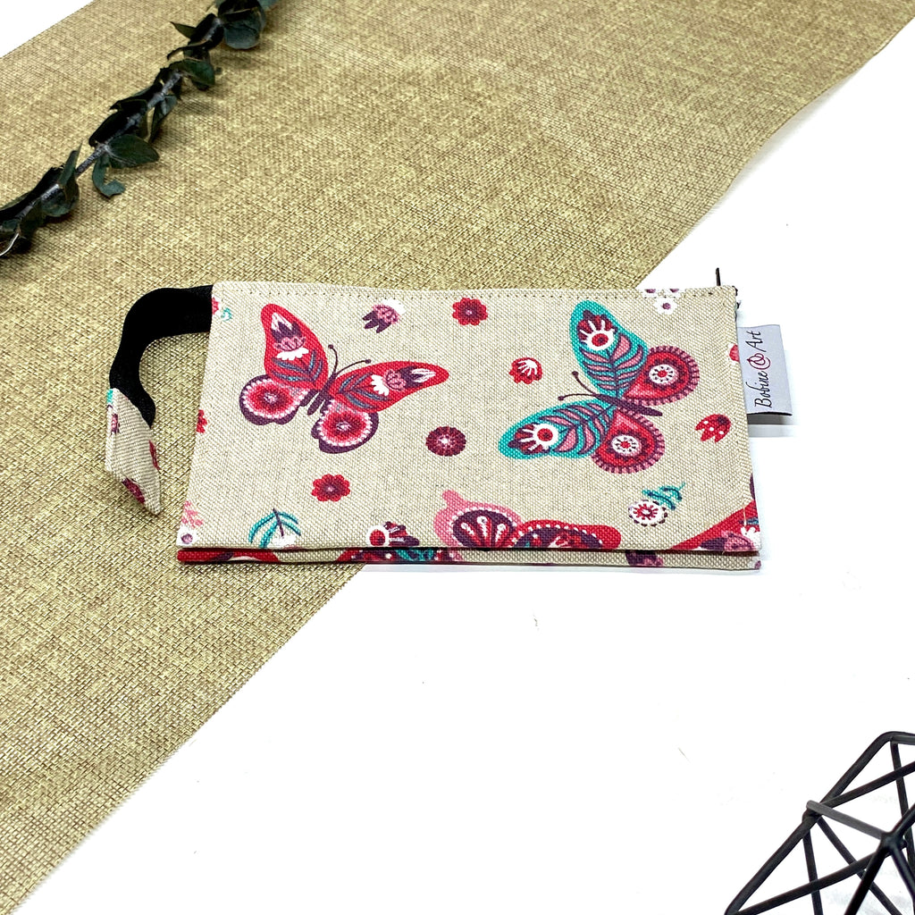 Trousse de toilette artisanale fermée en tissu avec motif papillons colorés et double compartiment imperméable.