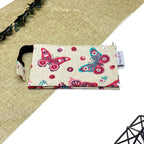 Trousse de toilette artisanale fermée en tissu avec motif papillons colorés et double compartiment imperméable.
