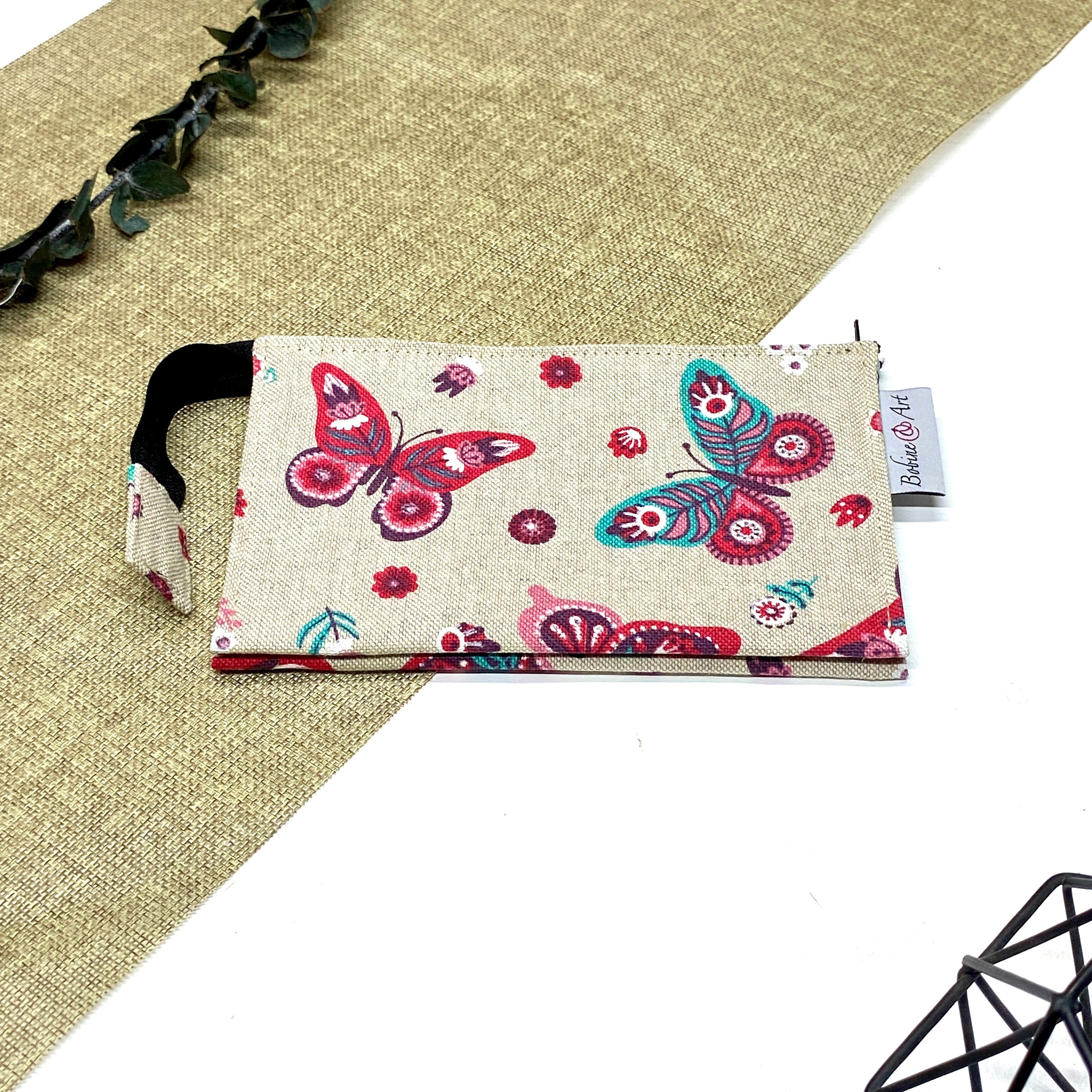 Trousse de toilette artisanale fermée en tissu avec motif papillons colorés et double compartiment imperméable.