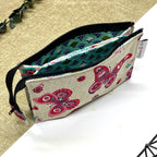 Trousse de toilette artisanale ouverte en tissu avec motif papillons roses, double compartiment et intérieur imperméable.